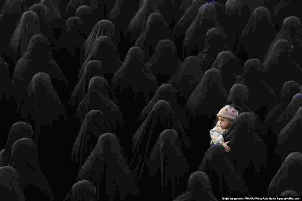A woman holds a child as people gather for the funeral of Sadegh Omidzadeh and Mohammad-Amin Samadi, members of Iran's Islamic Revolution Guards Corps (IRGC), in Tehran, Iran.