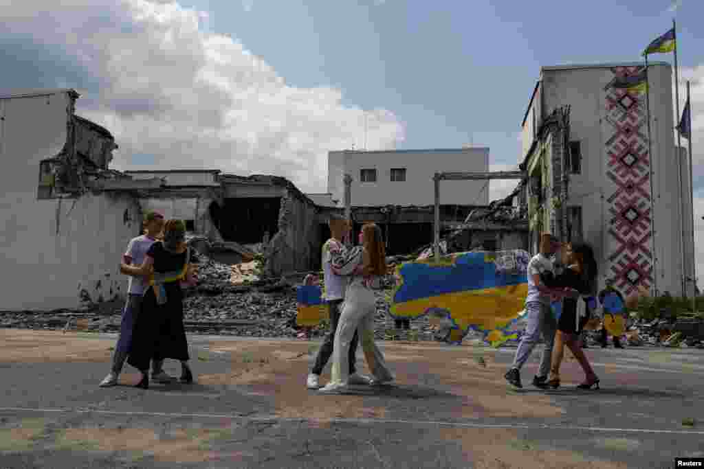 Graduates of a local lyceum dance in front of the local Palace of Culture destroyed by a Russian military strike, as they celebrate the last day of school in the town of Derhachi, Kharkiv region, Ukraine, June 17, 2023.
