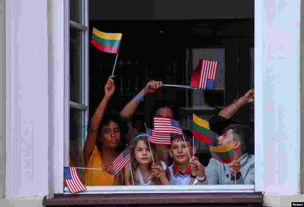Children look trough a window as they await a speech by U.S. President Joe Biden speech at Vilnius University during a NATO leaders summit in Vilnius, Lithuania.