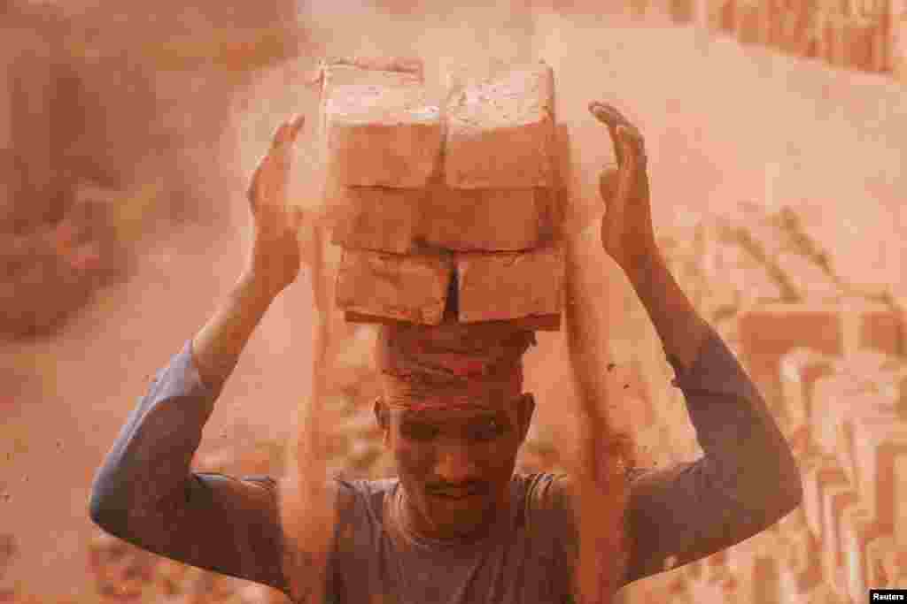 A worker loads bricks on his head in the dusty working environment of a brick factory in Dhaka, Bangladesh.