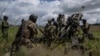FILE - Ukrainian service members prepare to fire at Russian positions with a U.S.-supplied M777 howitzer in Kharkiv region, Ukraine, July 14, 2022.