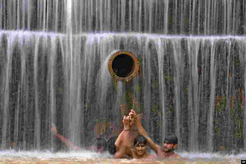 Young men cool themselves off in a waterfall as temperatures reached 36C (96.8F) in Islamabad, Pakistan.