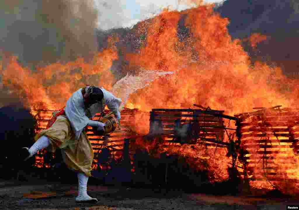 A Buddhist monk splashes water on a bonfire at the fire-walking festival, called Hiwatari Matsuri in Japanese, at Mt. Takao in Tokyo.