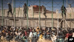 FILE - Askari wa kuzuia ghasia wakizingira eneo wakati wahamiaji walipowasili katika ardhi ya Uhispania na kuvuka wigo uliokuwa unatenganisha eneo la Melilla na Morocco huko Melilla, Uhispania, Juni 24, 2022. 