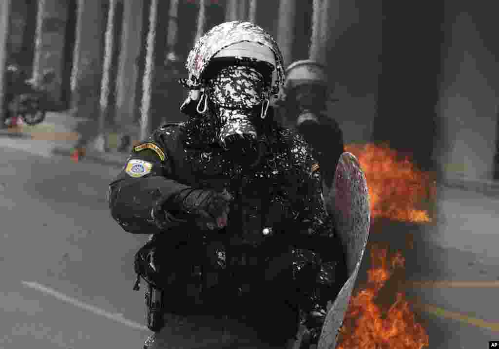 A riot policeman is covered with white paint thrown by protesters during clashes in the northern port city of Thessaloniki, Greece. Widespread strikes in Greece disrupted transport services, halting ferries and trains, in protests timed to coincide with the anniversary of a deadly rail crash a year ago. 
