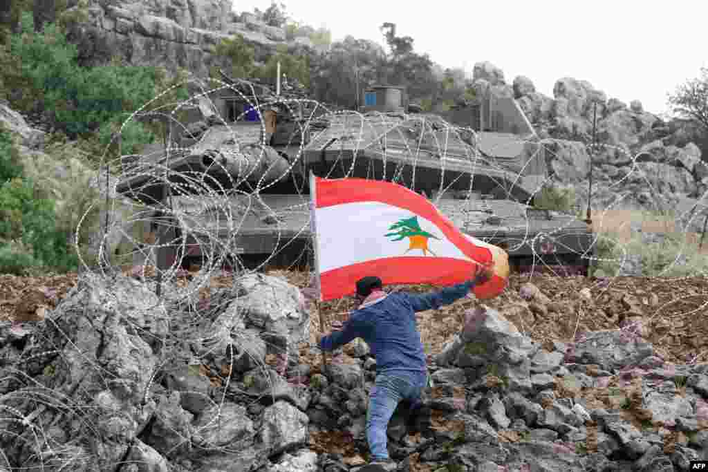 A Lebanese protester plants the national flag across the fence from an Israeli tank during an anti-Israeli demonstration near the "blue line" area, a demarcation line drawn by the U.N. to mark Israel's withdrawal from southern Lebanon in 2000, near the Lebanese southern village of Kfar Shuba.