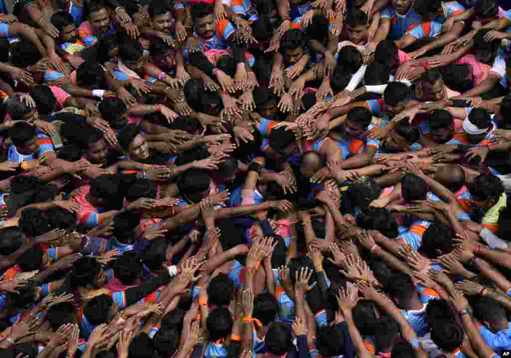 People pray before forming a human pyramid to break the "Dahi handi," an earthen pot filled with curd, as part of celebrations to mark Janmashtami festival in Mumbai, India.