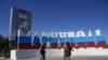 Російські солдати йдуть повз назви Маріуполя, перефарбовану в російського прапора, 12 червня 2022 року (AP Photo).
