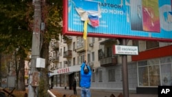 Мешканець Херсона знімає російський прапор із білборда у звільненому Херсоні. Фото зроблене 14 листопада 2022 року. Фото: AP/Efrem Lukatsky