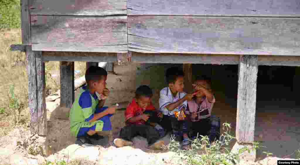 Seorang anak laki-laki mencoba menjilat lelehan es lilin dari celana abangnya di Pangambatan, Humbang Hasundutan, Sumatra Utara. (Foto: Hadengganan Sianturi/Kontes Foto VOA)