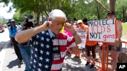 Pripadnik NRA zatvara uši prstima dok hoda pored demonstranata, tokom godišnje konvencije NRA, u Hjustonu, Teksas, 27. maja 2022.