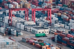 FILE - A cargo truck drives amid stacked shipping containers at the Yangshan port in Shanghai, China, March 29, 2018.