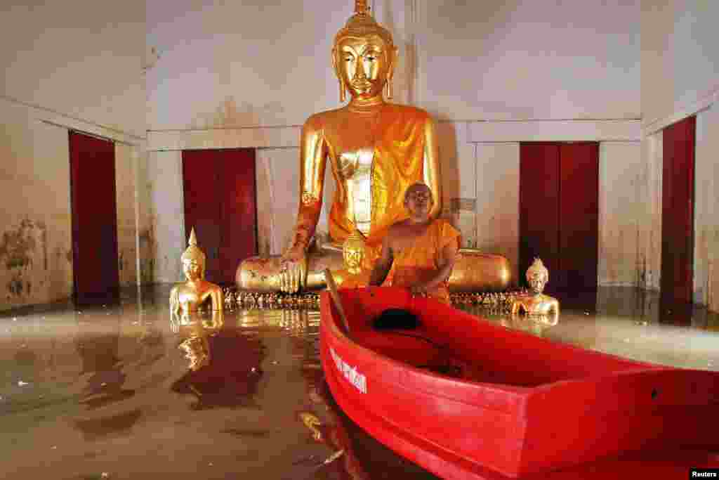 Seorang Biksu Buddha mendorong perahu plastik kecil saat ia menunjukkan kuilnya yang dilanda banjir kepada wartawan di distrik Ban Bang, provinsi Ayutthaya, Thailand.