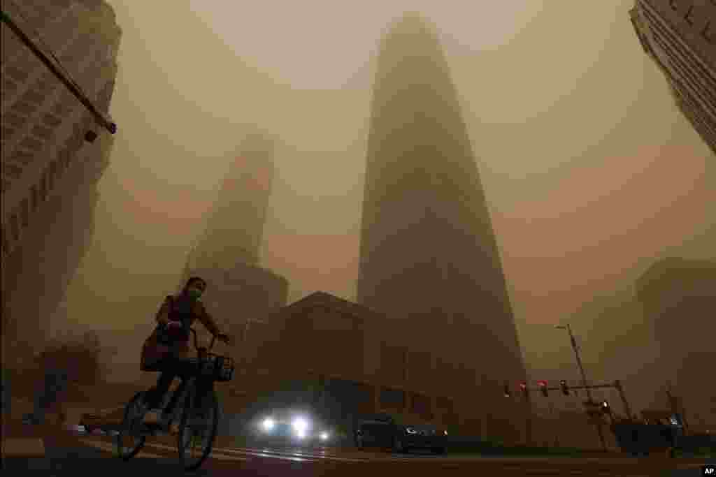 A cyclist and motorists move past office buildings amid a sandstorm during the morning rush hour in the central business district in Beijing, China.