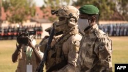 Le président malien de transition, le colonel Assimi Goïta (à droite) regarde après avoir déposé une gerbe sur le monument aux morts, lors de la cérémonie célébrant la fête nationale de l'armée, à Kati, le 20 janvier 2022.