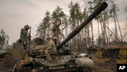 Украинские солдаты осматривают российский танк, подбитый под Киевом, Украина, 31 марта 2022 г. (фото AP Photo/Vadim Ghirda)