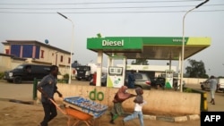 A vendor pushes wheelbarrow past a filling station dispensing diesel to motorists at Warewa, along Lagos Ibadan expressway, Ogun State, southwest Nigeria, on March 14, 2022.