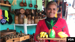 La artesana María Medina muestra algunas de las piezas talladas en madera que fabrica junto a su familia. [Carolina Alcalde/VOA]