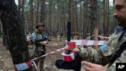 Oleg Kotenko, kamishna anayehusika na masuala ya watu wasiojulikana waliko katika mazingira maalum, anaangalia makaburi yasiyotambulika ya raia na wanajeshi wa Ukraine katika eneo lilotekwa na Ukraine huko Izium, Sept. 15, 2022.