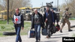 Petugas Palang Merah Internasional mengawal warga sipil yang dievakuasi dari Mariupol, Ukraina selatan hari Minggu (1/5). 