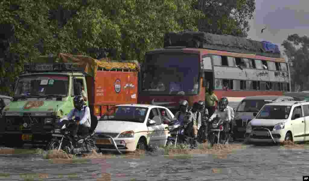 Commuters travel on a flooded road after a rise in the water levels of the Yamuna River in New Delhi, India, June 20, 2013.