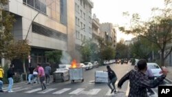 Katika picha hii , waandamanaji wawarushia mawe polisi wa kupambana na ghasia nchini Iran wakati wa maandamano ya kupinga kifo cha mwanamke aliyewekwa mahabusu kwa kukiuka maadili ya mavazi katika taifa hilo la kiislamu, Septemba 20, 2022. Picha ya AP