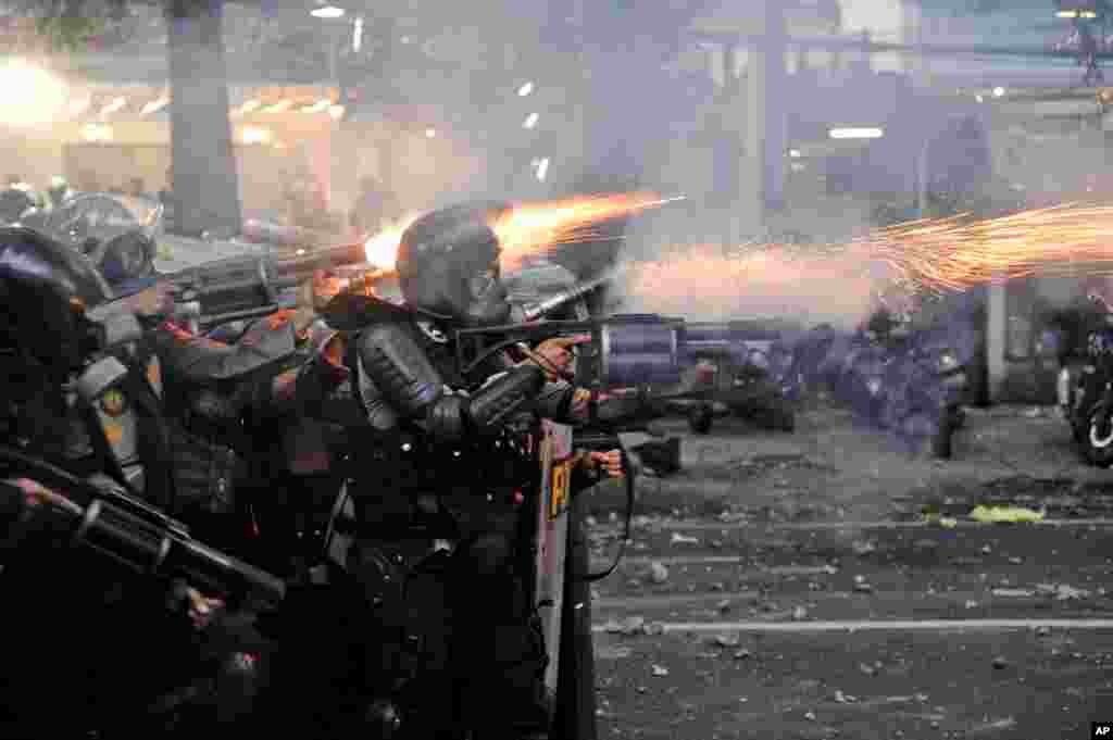 Police officers fire tear gas launchers during a clash with student protesters in Bandung, West Java, Indonesia. Thousands of students and workers protested against a new law they say will cripple labor rights and harm the environment.