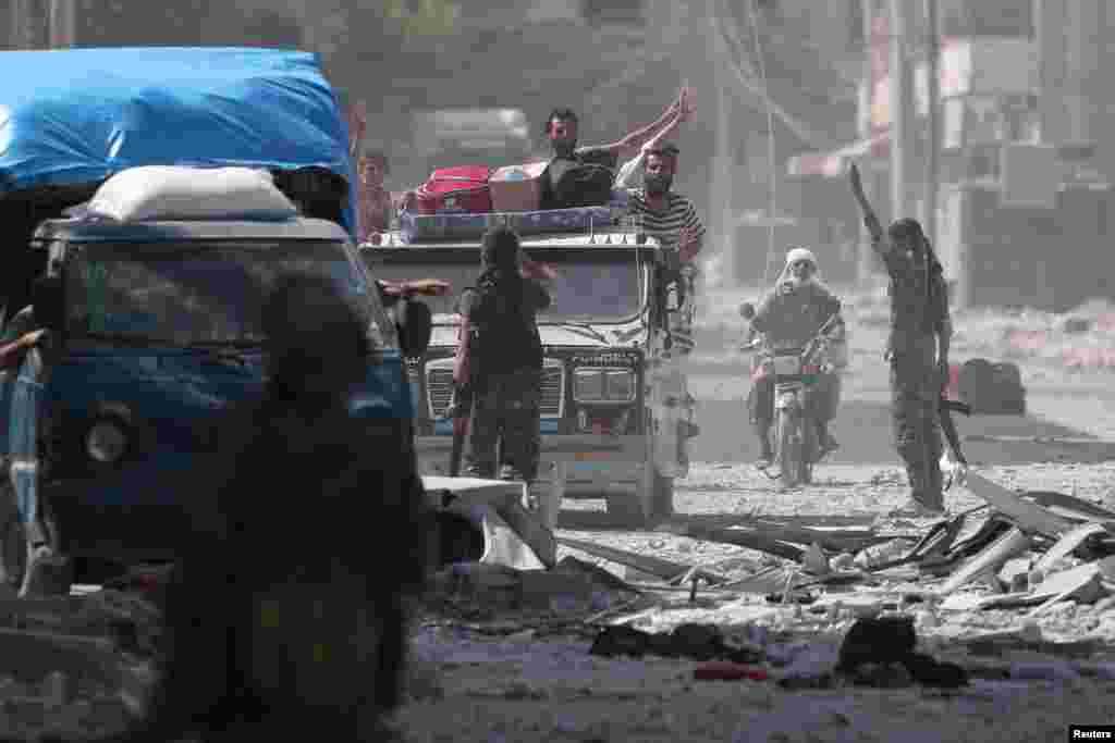 Para pejuang Pasukan Demokratik Suriah (SDF) menyapa warga sipil yang dievakuasi dari kota Manbij yang dikuasai ISIS di Aleppo, Suriah (12/8). (Reuters/Rodi Said)