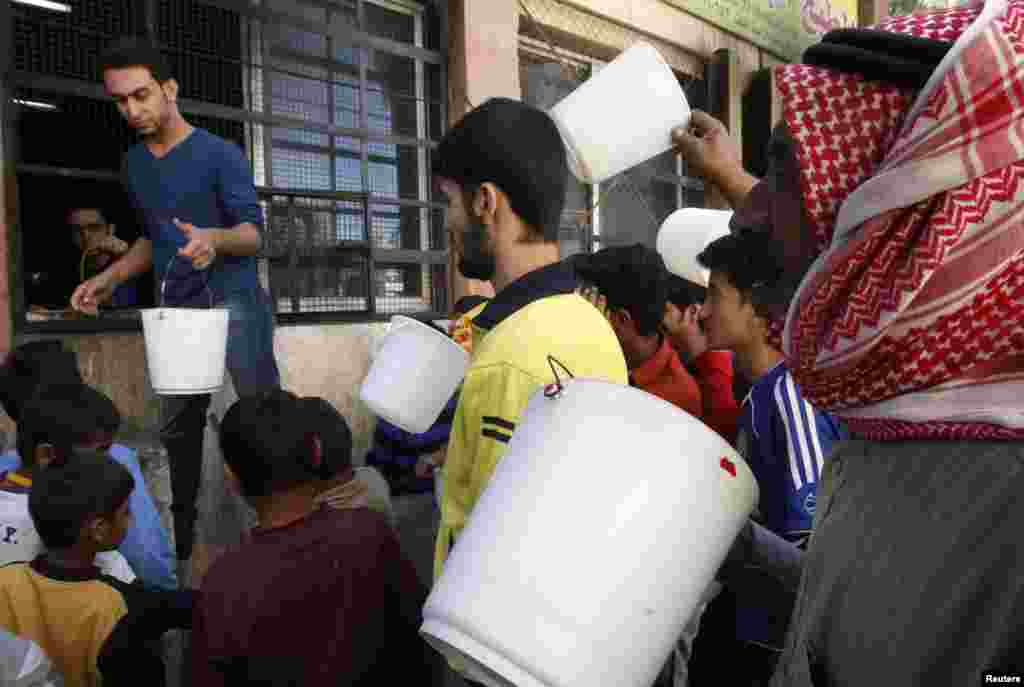 Para warga membawa ember sambil mengantre makanan gratis dari sebuah dapur umum di Raqqa, Suriah (7/10).