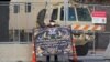 Un manifestante sostiene un cartel frente a la cerca fortificada y el vehículo de la Guardia Nacional que protege el Centro de Gobierno del condado de Hennepin, el 1 de abril de 2021, en Minneapolis.
