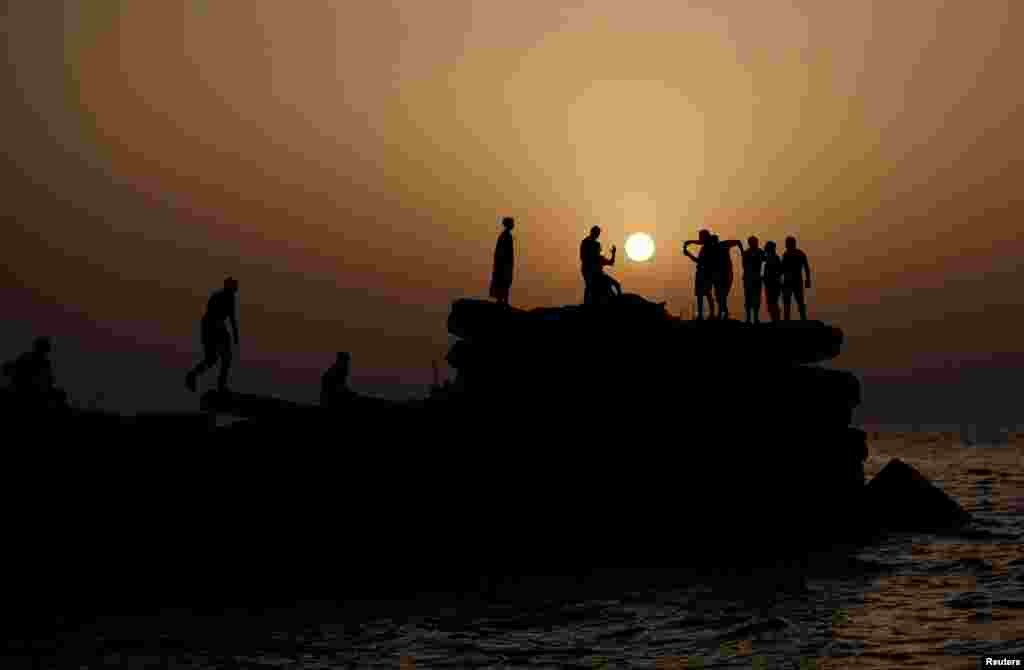 Palestinians are seen during sunset, at the seaport of Gaza City.