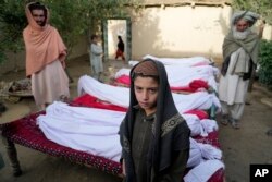 Warga berdiri di sekitar mayat korban yang tewas akibat gempa bumi di desa Gayan, di provinsi Paktika, Afghanistan, Kamis, 23 Juni 2022. (AP/Ebrahim Nooroozi)