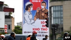 FILE - Motorists wearing face masks wait at a traffic light amid Vietnam's nationwide social isolation effort as a preventive measure against the spread of COVID-19 coronavirus in Hanoi, April 6, 2020.