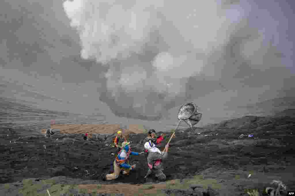 .Para penduduk desa menangkap sesajen uang logam yang dilemparkan oleh umat Hindhu suku Tengger selama perayaan festival Yadnya Kasada, di kawah Gunung Bromo di Probolinggo, Indonesia. Selama festival tahunan, suku Tengger mendaki Gunung Bromo, sebuah gunung berapi aktif, dan mencari berkah dari dewa utama Hyang Widi Wasa dengan memberikan sesajen yang terdiri dari beras, buah-buahan, binatang ternah, dan hasil bumi setempat. 