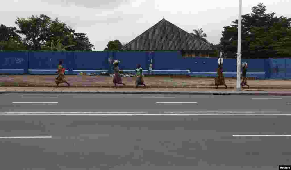 Congolese women run for safety along a deserted street during a clash near the state television headquarters in Kinshasa, Dec. 30, 2013.