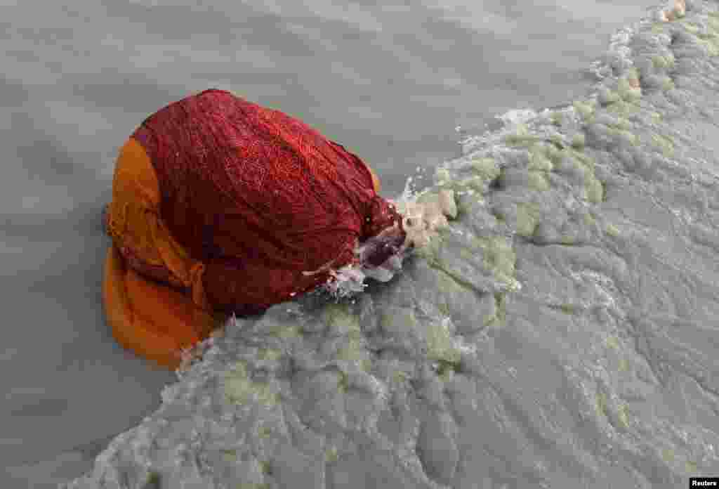 A female Hindu pilgrim takes a dip at the confluence of the Ganges River and the Bay of Bengal at Sagar Island, south of Kolkata, India, Jan. 14, 2013. Hindu monks and pilgrims are making an annual trip to Sagar Island for the one-day festival of "Makar Sankranti."