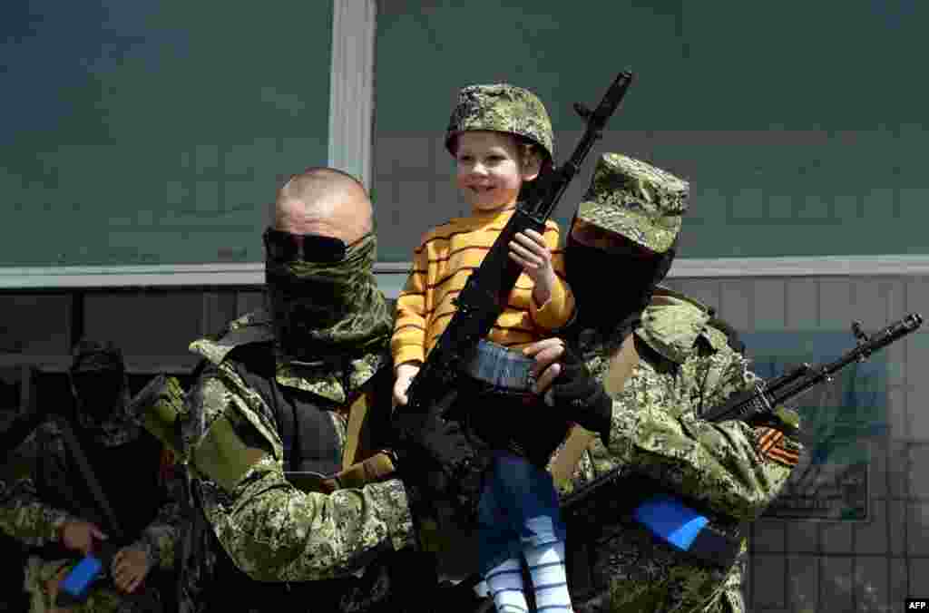 Dua milisi pro-Rusia di kota Kostyantynivka, Ukraina timur berpose dengan seorang anak kecil.