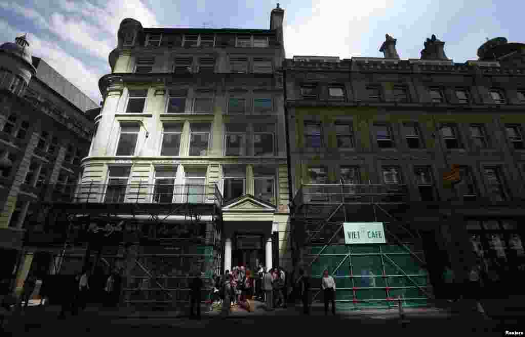 Pedestrians gather outside scaffoldings built to protect two shops from an intense beam of sunlight reflected off the Walkie Talkie tower in central London. The Walkie Talkie tower that reflects sunlight at an intensity capable of melting parts of a car became the latest attraction in the city's financial district as the developers acted to find a quick fix.