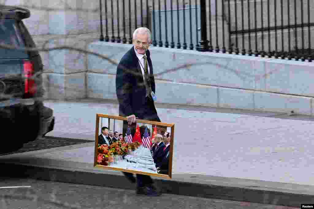 White House advisor Peter Navarro leaves the West Wing of the White House with a photograph of U.S. President Donald Trump and Chinese President Xi Jinping, in Washington, D.C., Jan. 13, 2021.