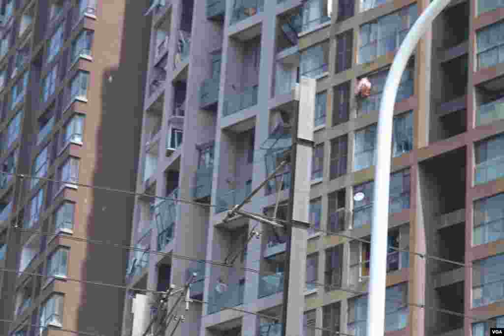 天津爆炸事故現場,核心爆炸區週圍多座居民樓窗戶被震碎,高速公路橋樑受損,多輛大貨車被炸翻,小汽車起火或被砸,多名當地居民仍逗留在事故現場。(美國之音記者東方拍攝)