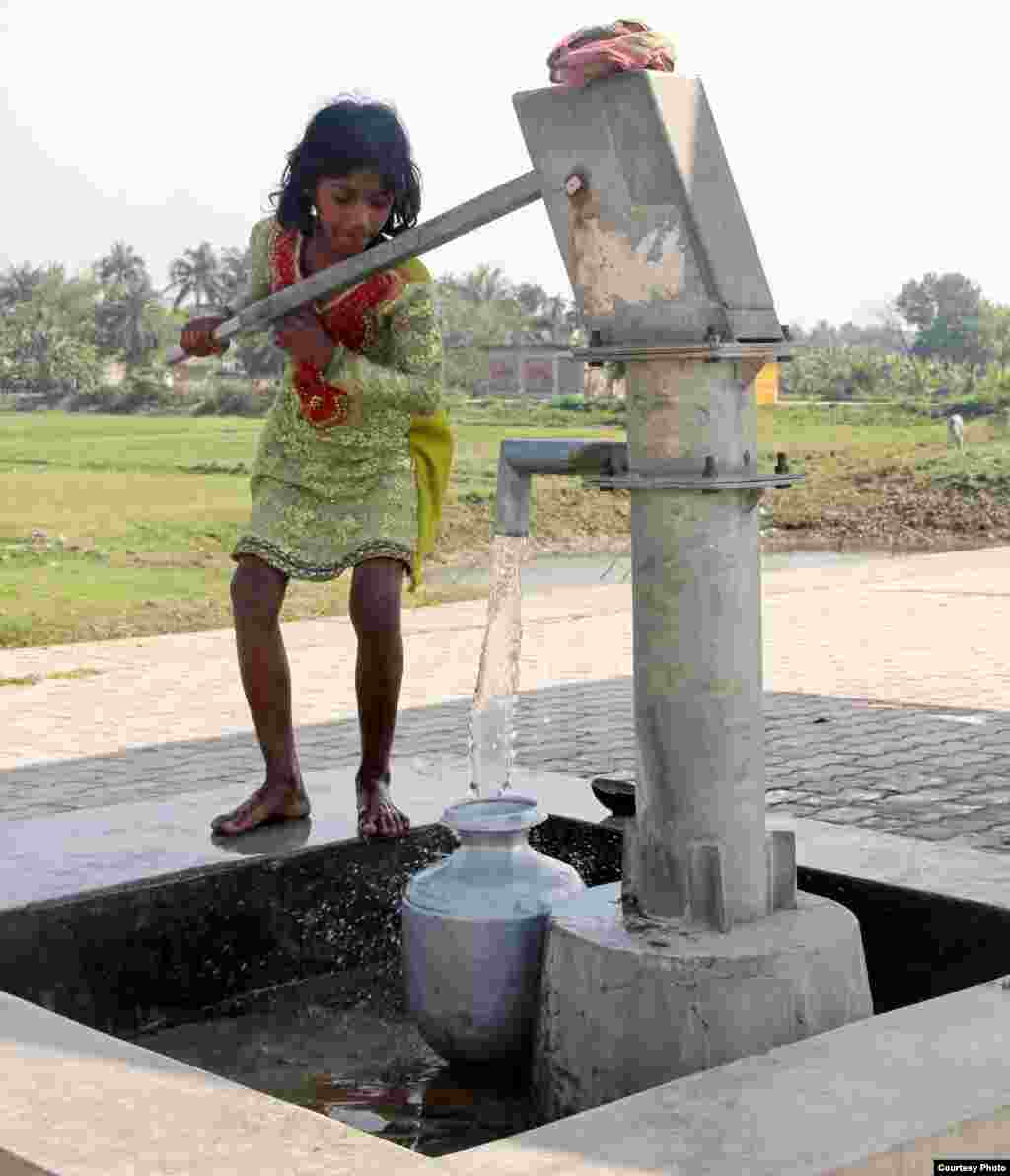 Seorang gadis desa mengisi wadah air minum di stasiun kereta Uttar Radhanagar di Bengal Barat, India. (Foto: Chandan Ghosh/India/pembaca VOA)