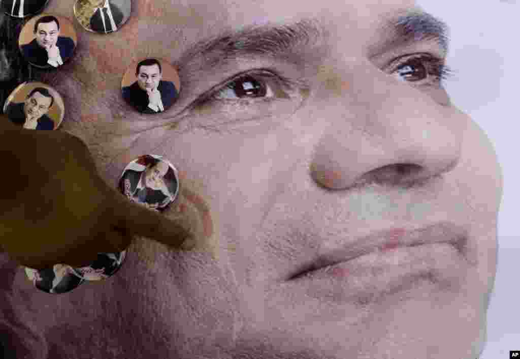Seorang pria menempelkan foto-foto mantan presiden Mesir Hosni Mubarak di sebuah poster kandidat presiden Mesir Abdel-Fattah el-Sissi di Kairo (4/5). (AP/Amr Nabil)