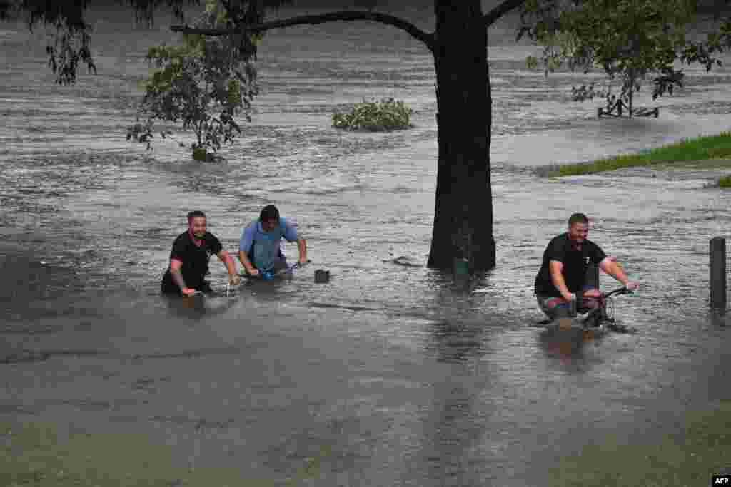 People ride their bicycles through a flooded park on the banks of Nepean river in Penrith suburb as Sydney, Australia, braced for its worst flooding in decades after record rainfall caused its largest dam to overflow.