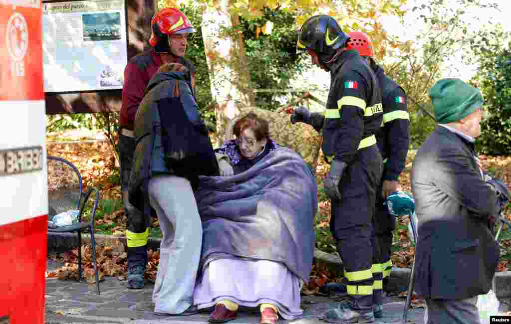 Petugas pemadam kebakaran mengevakuasi seorang perempuan menyusul gempa di Norcia, Italia (30/10). (Reuters/Remo Casilli)