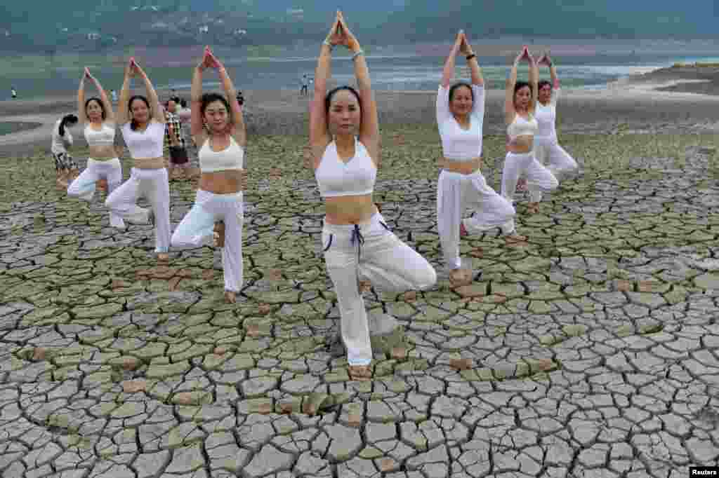 Women perform yoga on a dried river bank in Yunyang county, Chongqing Municipality, China, Aug. 21, 2016.