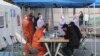 Medical staff wearing protective suits talk with people with suspected symptoms of new the coronavirus, at a testing facility in Seoul, South Korea, March 4, 2020. 