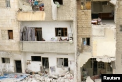 Children stand on a balcony of a damaged building at a site hit at dawn by an airstrike in the rebel-controlled town of Ariha in Idlib province, Syria, Feb. 27, 2017.