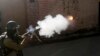 An Indian policeman fires tear smoke shell on Kashmiri protesters in Srinagar, India, Thursday, April 12, 2018. 