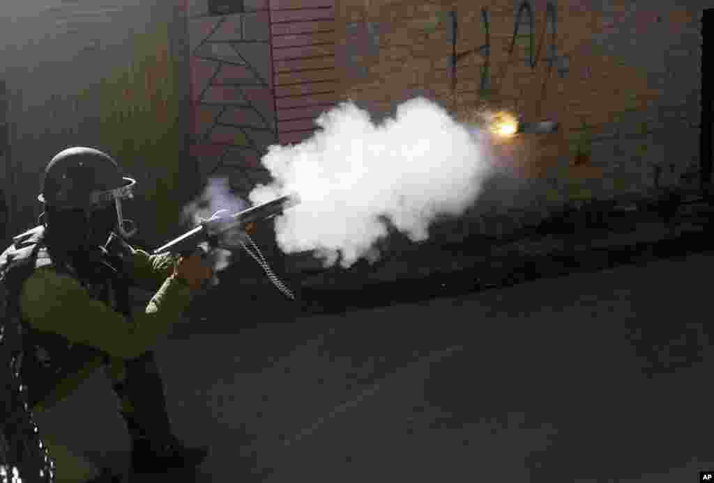 An Indian policeman fires tear smoke shell on Kashmiri protesters in Srinagar, India, Thursday, April 12, 2018.