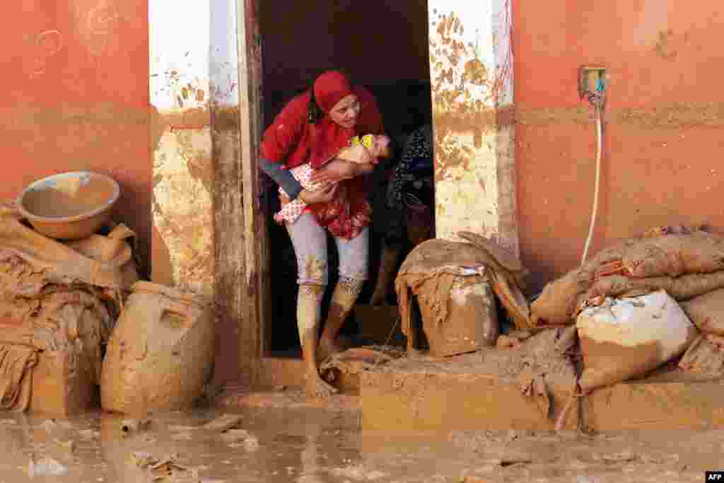A woman carrying her baby, stands on her doorstep in Ras Gharib, near the mouth of the Gulf of Suez in the Red Sea governorate, after flooding in parts of Egypt caused by torrential rains, Oct. 29, 2016.